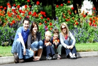 Das Bild zeigt eine Familie vor einem Blumenbeet.