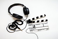 Das Bild zeigt Kopfhörer und eine Film-ab-Klappe.