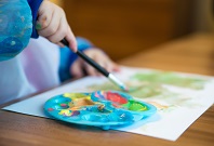 Kind malt mit Pinsel und Farbe