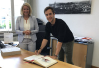 Badminton-Spieler Mark Lamsfuß trägt sich im Goldenen Buch der Stadt ein. Neben ihm steht Bürgermeisterin Anne Loth.